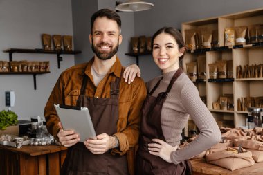 Beyaz satıcılar, yerel eco dükkanında gülümseyen ve tablet bilgisayar kullanan kadın ve erkekler.