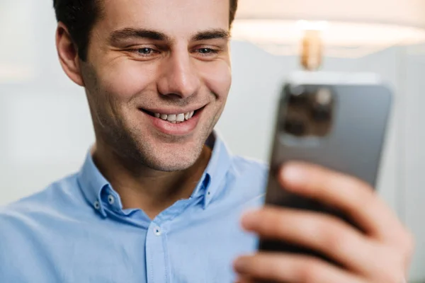 Sonriente Joven Empresario Guapo Usando Teléfono Móvil Mientras Está Sentado — Foto de Stock