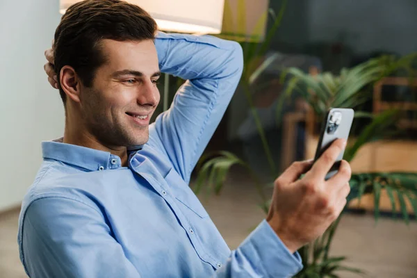 Sonriente Joven Empresario Guapo Usando Teléfono Móvil Mientras Está Sentado — Foto de Stock