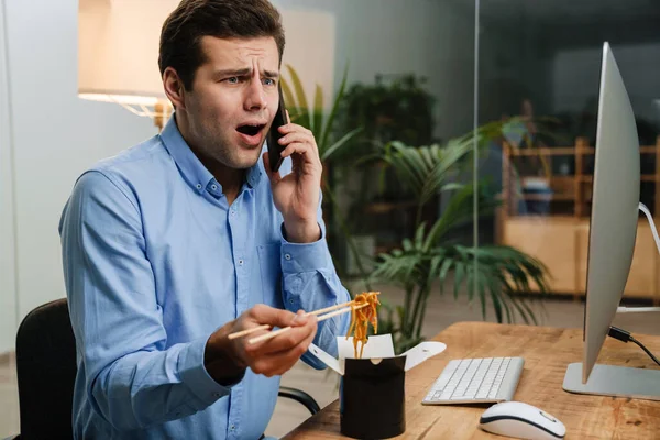 Confundido Joven Hombre Negocios Guapo Usando Teléfono Móvil Mientras Almuerza — Foto de Stock