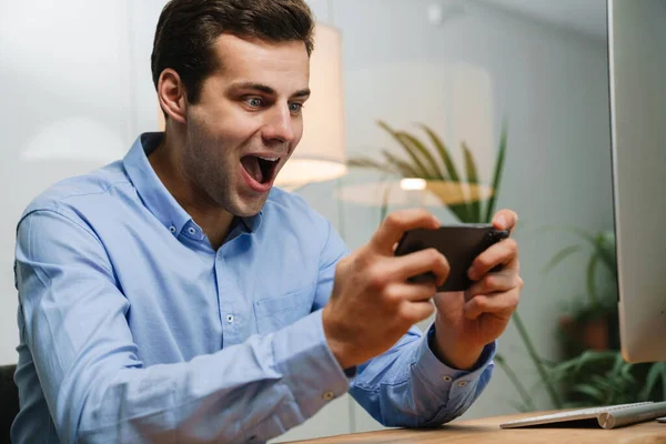 Feliz Joven Empresario Usando Smartphone Celebrando Éxito Lugar Trabajo —  Fotos de Stock