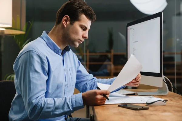 Giovane Imprenditore Attraente Pensieroso Guardando Attraverso Documenti Mentre Seduto Alla — Foto Stock