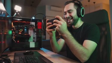 Kazanan oyuncu evinde güçlü bir bilgisayarın yanında otururken akıllı telefonuyla oynuyor.