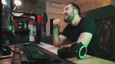 Olumlu bir oyuncu evde oturup pizza yerken güçlü bilgisayarına bakar.