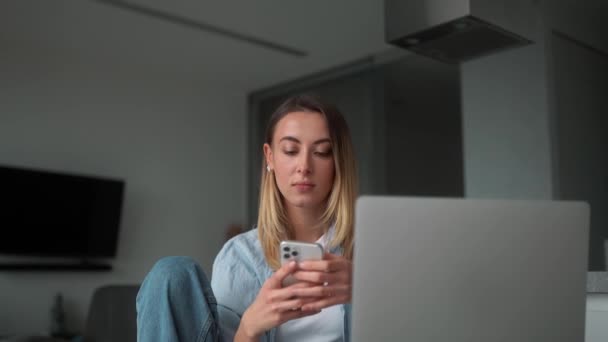 Mujer Pensativa Mirando Teléfono Sosteniéndolo Las Manos Mientras Está Sentada — Vídeos de Stock