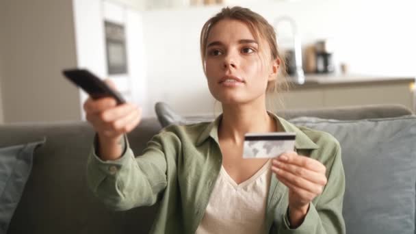 Mulher Sorrindo Inserindo Número Cartão Banco Usando Controle Remoto Enquanto — Vídeo de Stock