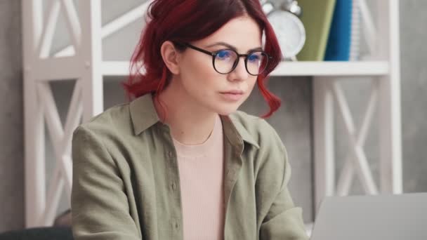 事務所のテーブルに座りながら眼鏡をかけた本気の女が働いている — ストック動画