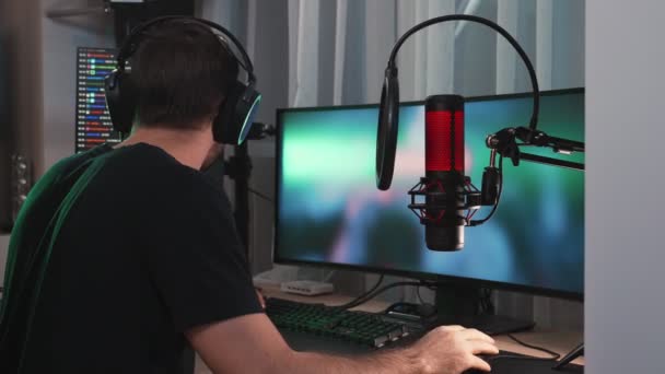 家に座ってマイクに話をしながら 緑の画面表示とプロの強力なコンピュータ上でオンラインビデオゲームをストリーミング肯定的な男のゲーマーの側面図 — ストック動画