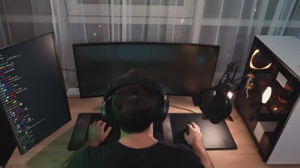 イヤフォンを身に着けている男のゲーマーのトップビューは 自宅に座ってプロの強力なコンピュータ上のオンラインビデオゲームをストリーミングしている — ストック動画