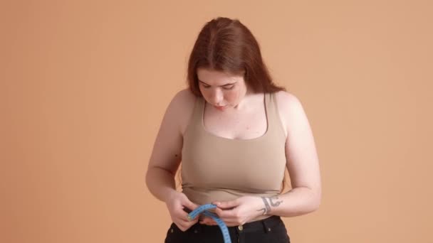 Счастливая Рыжеволосая Женщина Плюс Размер Использует Измерительную Ленту Стоящую Изолированно — стоковое видео