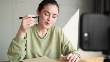 Telefonla konuşan mutlu bir kadın ve masada otururken aktif bir şekilde el kol hareketi yapan.