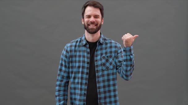 Usmívající Muž Kostkované Košili Ukazující Palec Stranu Šedém Studiu — Stock video