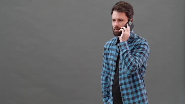 Uśmiechnięty Mężczyzna Koszuli Kratę Rozmawiający Przez Telefon Szarym Studiu — Wideo stockowe