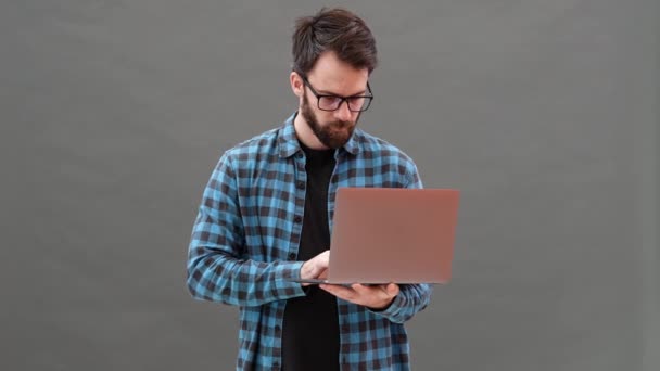 Hombre Sonriente Comprobando Algo Portátil Regocijándose Mientras Está Pie Estudio — Vídeo de stock