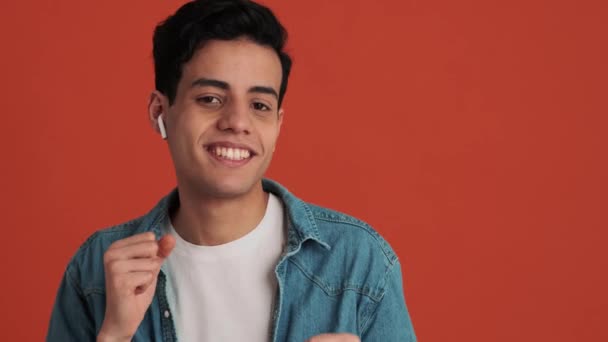 Hombre Árabe Sonriente Con Auriculares Inalámbricos Bailando Estudio Naranja — Vídeos de Stock