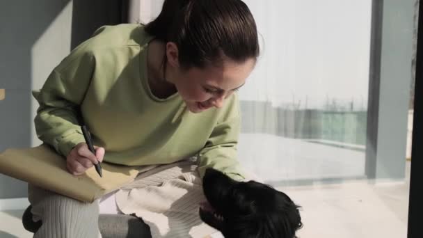 Крупный План Улыбающейся Женщины Гладящей Собаку Сидящей Окна Комнате — стоковое видео