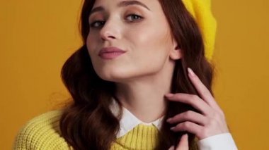 Pozitif bir kadının sarı stüdyoda dikilirken görünüşünü düzeltmesi.