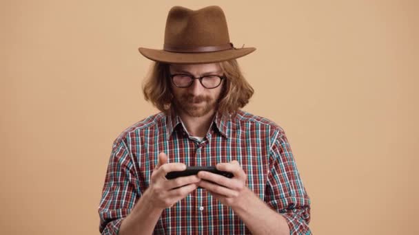 Uzun Saçlı Gözlüklü Bir Adam Telefonda Oyun Oynuyor Bej Rengi — Stok video