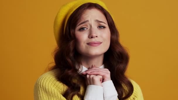 ベレー帽の女性が何かを求めていると黄色のスタジオで彼女の顔に手を上げると喜び — ストック動画