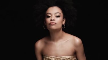 Siyah bir stüdyoda görüntüsünü düzelten mutlu bir kadın.