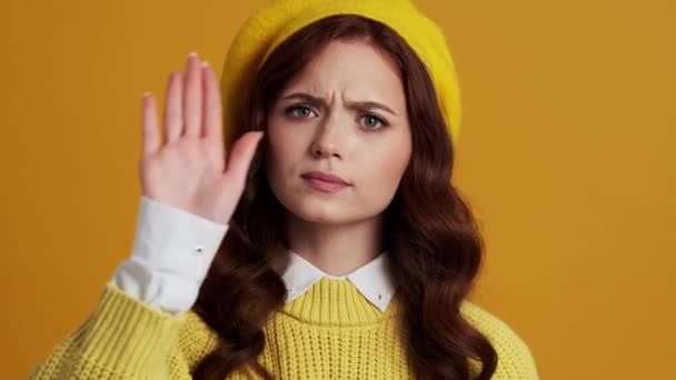 站在一个黄色的画室里 一个专心致志的女人的画像 用她的手掌做着一个停止的手势 — 图库视频影像