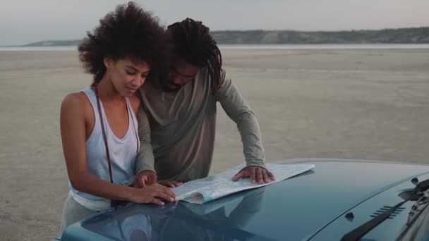 Sonriente Pareja Africana Pavimentando Una Ruta Con Mapa Capó Del — Vídeo de stock