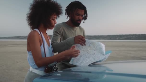 車のフードにマップとルートを舗装集中アフリカのカップル — ストック動画
