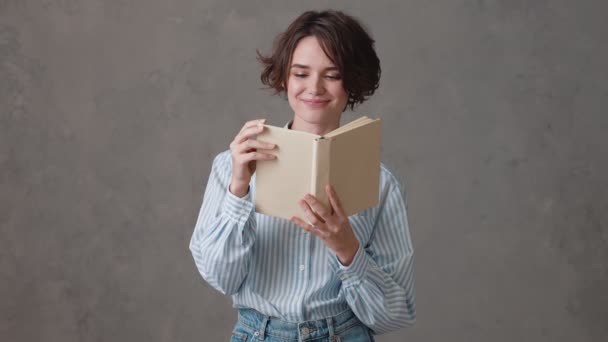 Feliz Mujer Pelo Corto Leyendo Libro Mientras Está Pie Estudio — Vídeo de stock