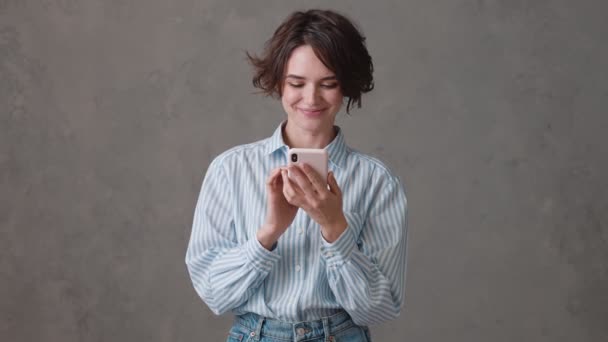 Mulher Cabelos Curtos Rindo Digitando Algo Telefone Enquanto Estava Estúdio — Vídeo de Stock