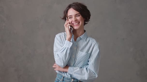 Mulher Sorridente Cabelos Curtos Falando Telefone Enquanto Estava Estúdio Cinza — Vídeo de Stock