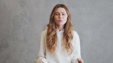 Kapüşonlu kadın gri stüdyodaki kelimeleri duyamaz.