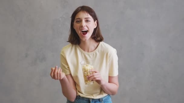Smějící Dívka Jíst Popcorn Zatímco Stojí Šedém Studiu — Stock video