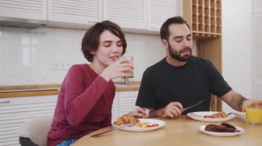 Yakışıklı genç bir çift kahvaltı yapıyor. Evdeki mutfaktaki masada oturuyor.