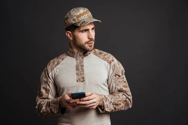 Allvarlig Militär Man Som Använder Mobiltelefon Och Tittar Sidan Isolerad — Stockfoto