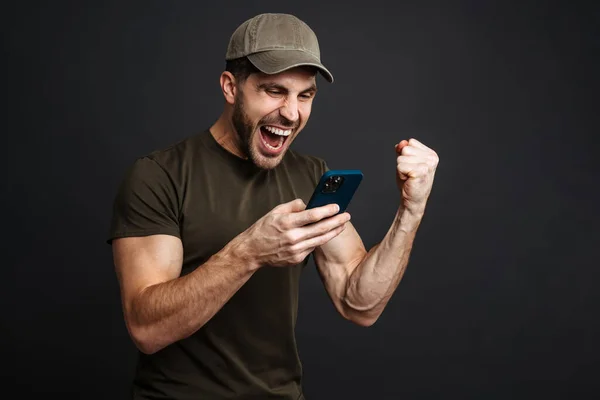 Militar Excitado Haciendo Gesto Ganador Mientras Utiliza Teléfono Celular Aislado — Foto de Stock