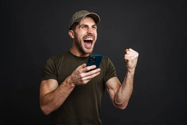 Spännande Militär Man Gör Vinnaren Gest När Använder Mobiltelefon Isolerad — Stockfoto