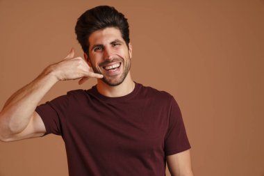 Mutlu, erkeksi bir adam gülümserken bej arka planda izole edilmiş cep telefonu hareketi gösteriyor.