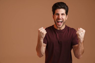 Heyecanlı erkeksi erkek çığlıklar atarken kazanan jest bej arka planda izole ediliyor