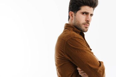 Kolları çaprazlanmış, beyaz arka planda poz veren erkeksi yakışıklı genç adam.