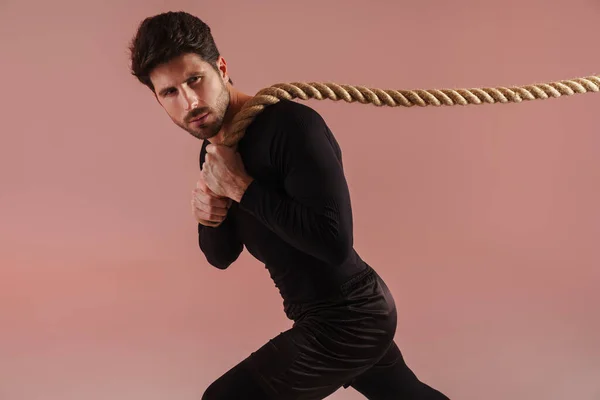 Confident Young Brunette Sportsman Pulling Rope Pink Wall Background — 스톡 사진