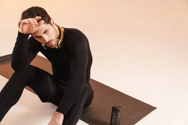 Deportista Atlético Cansado Con Auriculares Sentados Estera Durante Entrenamiento Aislado —  Fotos de Stock