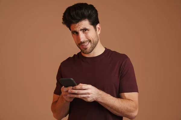 Pleased Masculine Man Using Mobile Phone Smiling Isolated Beige Background — Stock Photo, Image