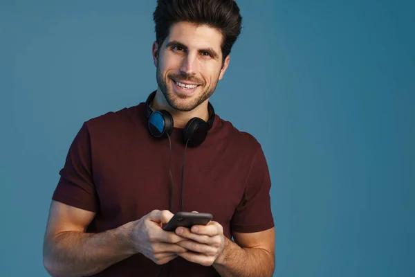 Smiling Handsome Man Headphones Using Mobile Phone Isolated Blue Background — Stock Photo, Image