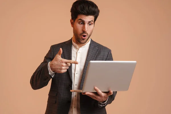 Homem Morena Chocado Segurando Apontando Dedo Para Seu Laptop Isolado — Fotografia de Stock
