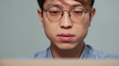 Ofiste dizüstü bilgisayarın önünde oturan konsantre Çinli adamın yakın çekim görüntüsü.