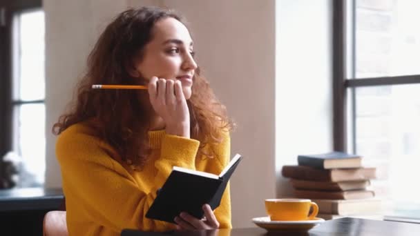 Een Positieve Vrouw Maakt Aantekeningen Haar Notitieboekje Zittend Het Café — Stockvideo
