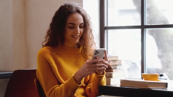 Una Mujer Sonriente Está Usando Teléfono Inteligente Sentado Café Dentro — Vídeos de Stock