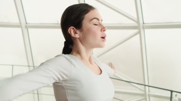 Kvinnan Träningsoverall Andas Och Sänker Armarna När Hon Står Gymmet — Stockvideo