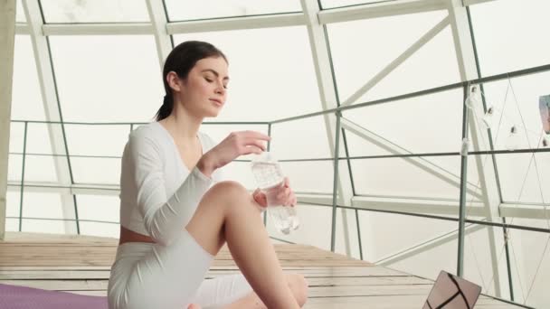 Mulher Positiva Bebendo Água Uma Garrafa Sentada Tapete Enquanto Olha — Vídeo de Stock
