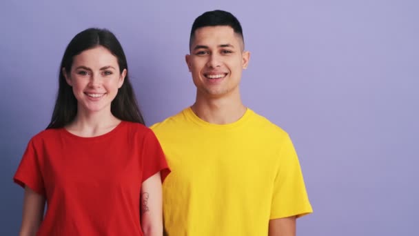 Casal Positivo Apontando Para Copyspace Enquanto Estava Estúdio Roxo — Vídeo de Stock